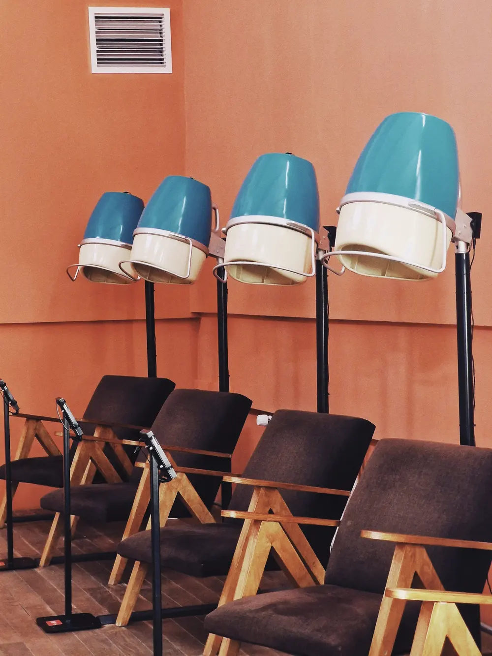 Retro salon z suszarkami kopułowymi przy pomarańczowej ścianie